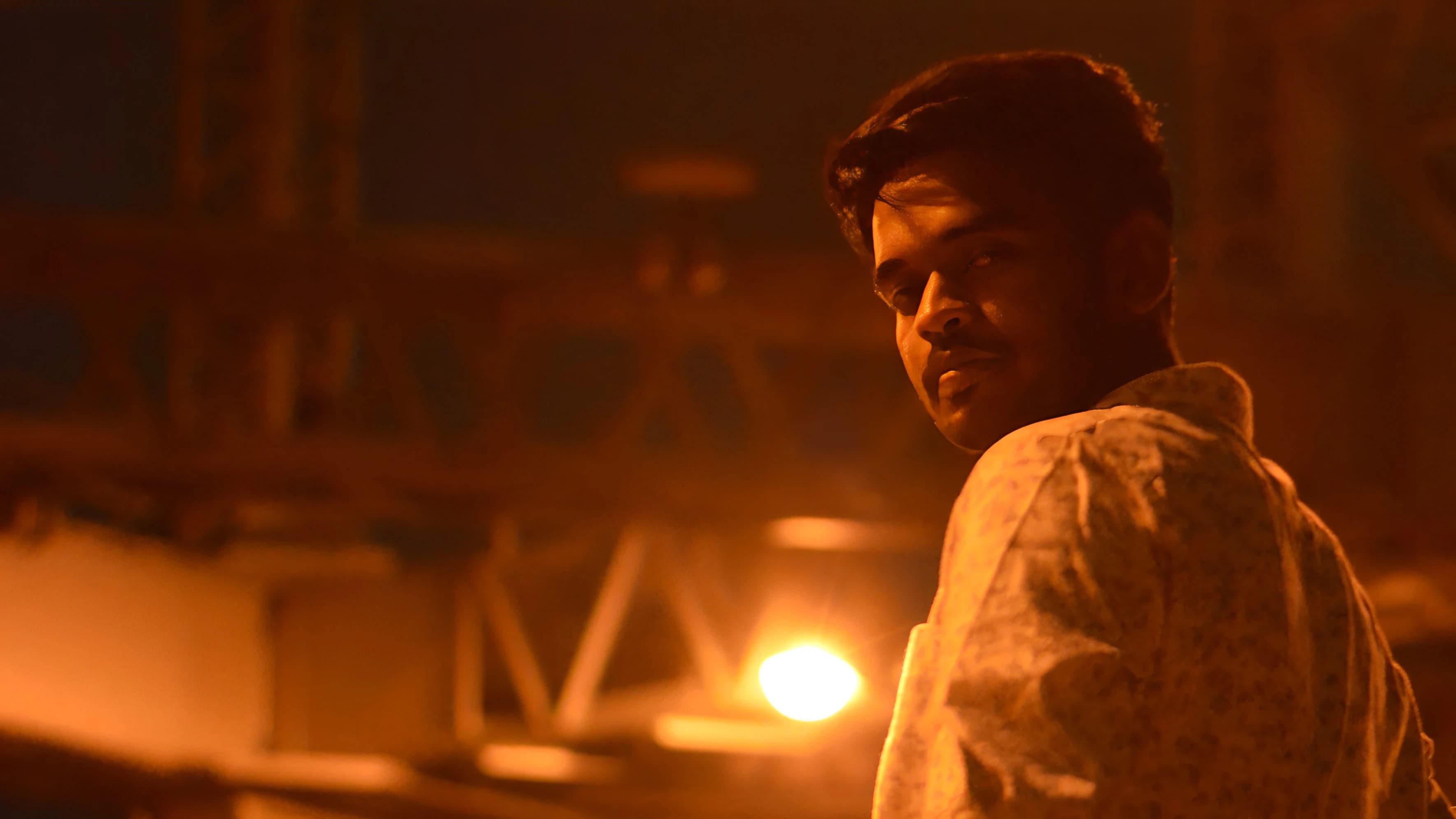 Portrait of Prabakaran, lit warm against a workshop background